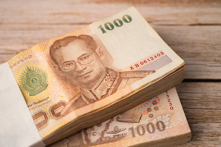 Stack of Thai baht banknotes on wooden background, business saving finance investment concept.の写真素材