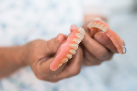 Asian elderly woman patient holding to use denture, healthy strong medical concept.