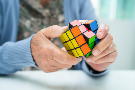 Bangkok, Thailand August 14, 2023 Alzheimer disease AD, Asian elderly woman patient playing Rubik cube game to practice brain training for dementia prevention.のeditorial素材