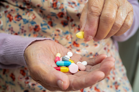 Asian senior woman patient holding antibiotics capsule pills  for treatment infection patient in hospital, Pharmacy drugstore concept.の写真素材