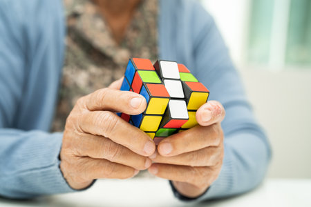 Bangkok, Thailand August 14, 2023 Alzheimer disease AD, Asian elderly woman patient playing Rubik cube game to practice brain training for dementia prevention.のeditorial素材