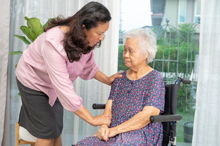 Caregiver help Asian senior woman on wheelchair with love at home.