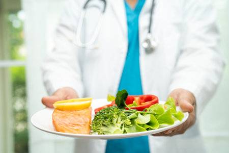 Nutritionist doctor holding healthy salmon steak and vegetable vitamin food for patient in hospital.の写真素材