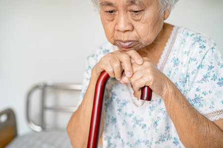 Asian elderly disability woman holding waling stick, wood cane, round handle, walking aid for help to walk.の写真素材