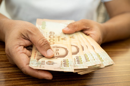 Asian business woman holding Thai banknote currency money.
