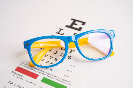 Glasses on eye testing exam chart to check eyesight accuracy of reading.の写真素材