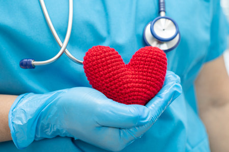 Doctor holding a red heart in hospital ward, healthy strong medical concept.