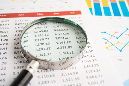 Magnifying glass on spreadsheet and graph paper. Financial development, Banking Account, Statistic,...