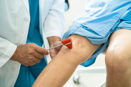 Asian doctor use hammer knock senior woman patient to check knee reflex, nerve and muscle in hospital.の写真素材