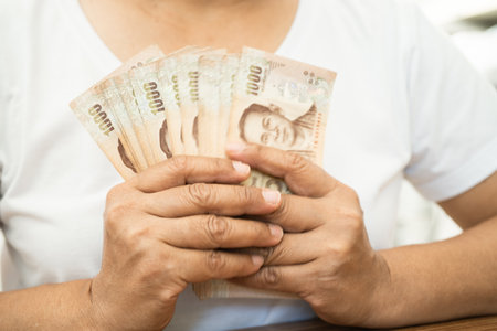 Asian business woman holding Thai banknote currency money.