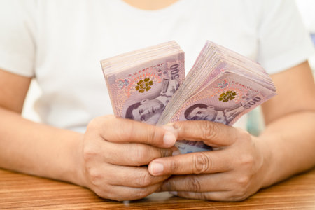 Asian business woman holding Thai banknote currency money.