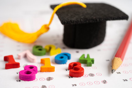 Graduation gap hat and pencil on answer sheet paper, Education study testing learning teach concept.の写真素材