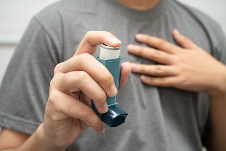 Asthma and chronic obstructive pulmonary disease COPD, Asian young man using metered dose inhaler MDI.の写真素材
