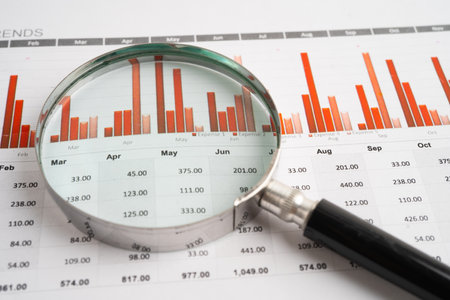 Magnifying glass on spreadsheet and graph paper. Financial data economy, Business.