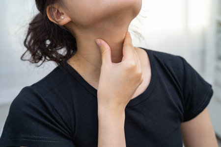 Asian woman touching her neck and throat for thyroid gland problem.の写真素材