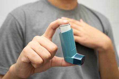 Asthma and chronic obstructive pulmonary disease COPD, Asian young man using metered dose inhaler...