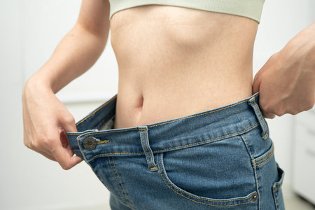 Young Asian woman losing weight wearing loose pants in oversize jeans.