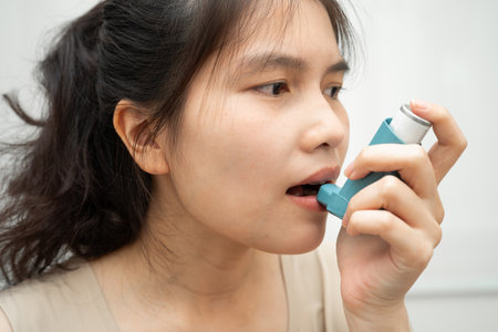 Asthma and chronic obstructive pulmonary disease COPD, Asian woman using metered dose inhaler MDI.の写真素材