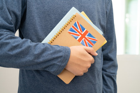 Learn English language, Asian teenage student hold book with flag in course at school.の写真素材
