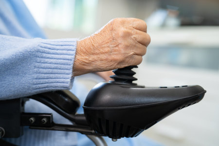 Asian senior woman patient on electric wheelchair with remote control at hospital.の写真素材