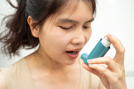 Asthma and chronic obstructive pulmonary disease COPD, Asian woman using metered dose inhaler MDI.の写真素材