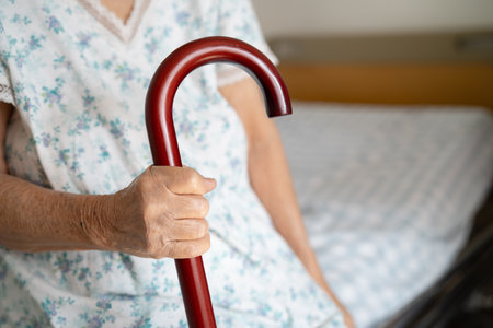 Asian elderly disability woman holding waling stick, wood cane, round handle, walking aid for help to walk.の写真素材