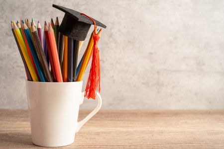 Graduation hat with pencil in cup with copy space.