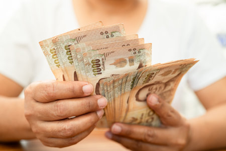 Asian business woman holding Thai banknote currency money.