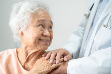 Caregiver holding hands Asian elderly woman patient with love, care, encourage and empathy at nursing hospital, healthy strong medical.の写真素材