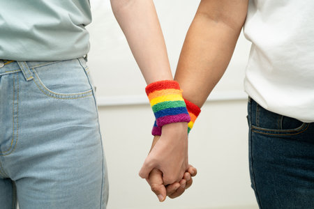 Asian LGBT couple woman holding hand wearing rainbow wristband.の写真素材