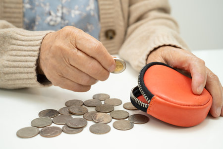 Asian senior or elderly old lady woman holding counting coin money in purse. Poverty, saving problem in retirement.の写真素材
