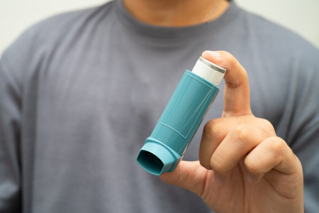 Asthma and chronic obstructive pulmonary disease COPD, Asian young man using metered dose inhaler MDI.の写真素材