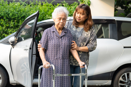 Caregiver help Asian elderly woman disability patient get in her car.の写真素材