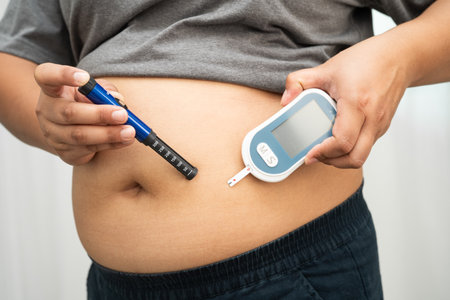 Asian woman injecting herself diabetes injecting insulin in stomach at home.