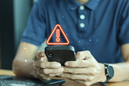 Notification smartphone concept. A young man using a phone with a warning symbol indicating the risk of data theft, Hacking passwords, and personal data.の写真素材