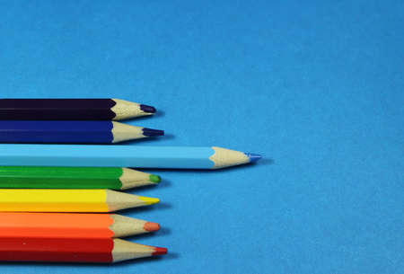 colored pencils on the left on a blue background, one blue pencil is highlightedの写真素材