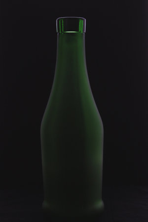 Green bottle on a black background. Studio shot with low key lighting.の写真素材