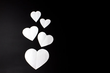 White paper hearts on black background. Valentine's day concept. copyspace.