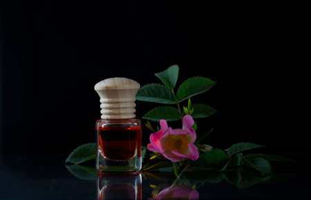 Essential oil in a bottle with rose flower on black background.の写真素材