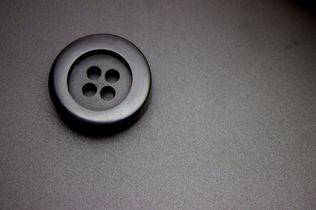 Close-up of a black button on a gray background. Shallow depth of fieldの写真素材