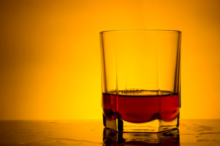 Glass of whiskey on a yellow background. Close-up. Selective focus.の写真素材