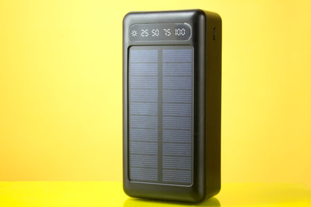 Portable solar-powered charger for a smartphone on a yellow background, close-up.の写真素材