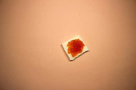 Toast bread with red caviar on a beige background.