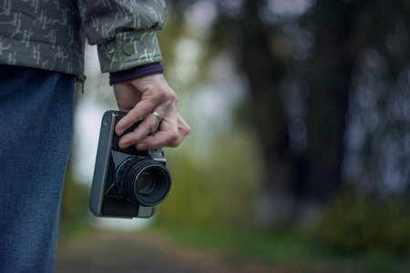A person holds an antique camera in their hand on the street. The background is blurred.の写真素材