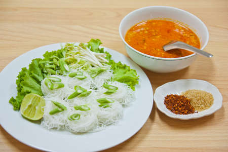 Thailand north-eastern style noodle, served with pork curry and seasoningの写真素材