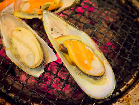 Grilling mussels on charcoal stoveの写真素材