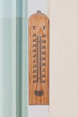 Classic thermometer hanging on edge of glass window and cement wallの写真素材