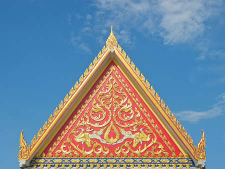Thai Buddhist temple gable with golden apex under blue sky