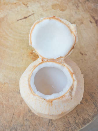Coconut white flesh in an openning coconut shell on wood tableの写真素材