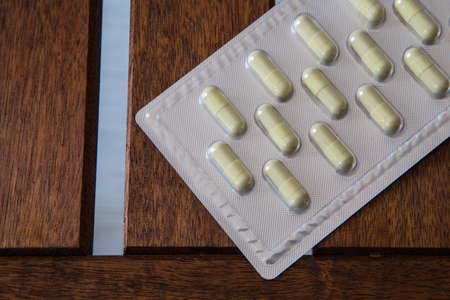 Capsule drug pack on brown wooden tableの写真素材
